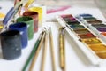 The child paints. Watercolor, gouache, paint brushes, colored and wax crayons, stickers. Set for drawing, creativity and hobbies Royalty Free Stock Photo