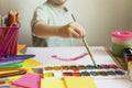 The child paints. Watercolor, gouache, paint brushes, colored and wax crayons, stickers. Set for drawing, creativity, hobbies Royalty Free Stock Photo