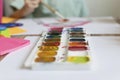 The child paints. Watercolor, gouache, paint brushes, colored and wax crayons, stickers. Set for drawing, creativity, hobbies Royalty Free Stock Photo