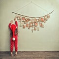 Child in pajamas and Christmas cap stretches for advent calendar with small gifts. kid counts days until new year