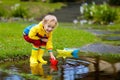 Child with paper boat in puddle. Kids by rain. Royalty Free Stock Photo