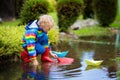 Child with paper boat in puddle. Kids by rain Royalty Free Stock Photo