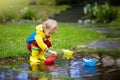 Child with paper boat in puddle. Kids by rain Royalty Free Stock Photo