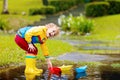 Child with paper boat in puddle. Kids by rain Royalty Free Stock Photo