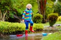 Child with paper boat in puddle. Kids by rain Royalty Free Stock Photo