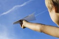 Child with paper plane against blue sky. Low angle view Royalty Free Stock Photo