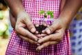 Child with parents hand holding young tree in egg shell together