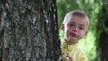 Child peeks out from behind tree and smiles, slow motion