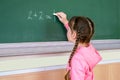 The child performs a learning task. Babe starts school in first grade.Little girl draws with chalk on a blackboard. School concept Royalty Free Stock Photo