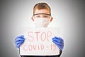 A child in personal protective equipment holding papers sign stop COVID-19. Warning coronavirus cloceup.