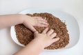 A child picks up buckwheat porridge, hands of a child and porridge on a white background