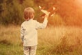 Child pilot aviator with plane at sunset, little boy playing with cardboard toy airplane outdoors, against summer sky background. Royalty Free Stock Photo