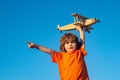 Child pilot showing or pointing copy space. Little boy with wooden plane. Boy with airplane on air, sky background.