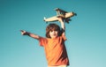 Child pilot showing or pointing copy space. Little boy with wooden plane. Boy with airplane on air, sky background.