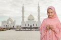 A child in a pink hijab with a beads in his hands Against the background of a white mosque. People religious lifestyle concept Royalty Free Stock Photo