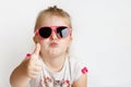 Child in pink sunglasses making funny face. positive girl thumbs up on a white background Royalty Free Stock Photo