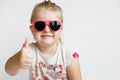 Child in pink sunglasses making funny face and smiling. positive girl thumbs up on a white background Royalty Free Stock Photo