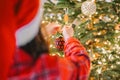 child in plaid pajamas decorate the Christmas tree with shiny balls.hands put balls on the branches Royalty Free Stock Photo