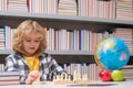 Child play chess in classroom. Kid playing chess. Child thinking near chessboard. Learning and growing children Royalty Free Stock Photo
