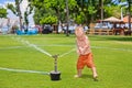 Child play, swim and splash under water sprinkler spray Royalty Free Stock Photo