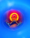 Child on the playground comes down in a big blue tunnel slide Royalty Free Stock Photo