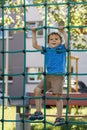 Boy In Adventure Park having fun in high wire park. Male toddler on climbing net Royalty Free Stock Photo