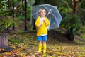 Child playing in autumn rain. Kid with umbrella