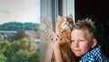 Child boy playing with ginger cat. Little kid with cat near window. Boy snuggling cute pet animal at home. Kids play Royalty Free Stock Photo