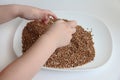 A child picks up buckwheat porridge, hands of a child and porridge on a white background