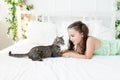 A child playing with a cat at home, a little girl with a cat lying on the bed, the concept of a child`s friendship with animals Royalty Free Stock Photo