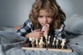 Child playing chess on bed. Child think about chess game. Intelligent, smart and clever school kid pupil. Games for Royalty Free Stock Photo