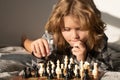 Child playing chess on bed. Thinking child. Chess game for kids. Intelligent, smart and clever school boy. Royalty Free Stock Photo