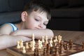 The serious child lost in thought playing chess. Playing board games, on coronavirus quarantine. The child playing chess Royalty Free Stock Photo