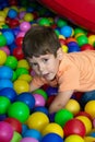 Child playing with colorful balls in playground ball pool. Activity toys for little kid. Kids happiness emotion having fun in ball Royalty Free Stock Photo