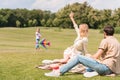 child playing with colorful kite and looking at parents sitting Royalty Free Stock Photo