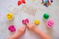 Child playing with colorful modeling clay with beads and sequins and sculpting heart figure. Home Education game with clay.