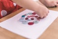 Child playing with different color and sizes buttons on a spiral shape drew on a white paper Royalty Free Stock Photo