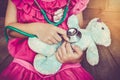 Child playing doctor or nurse with plush toy bear at home. Vintage tone effect. Royalty Free Stock Photo