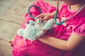 Child playing doctor or nurse with plush toy bear at home. Vintage tone effect. Royalty Free Stock Photo