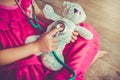 Child playing doctor or nurse with plush toy bear at home. Vintage tone effect. Royalty Free Stock Photo