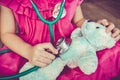 Child playing doctor or nurse with plush toy bear at home. Vintage tone effect. Royalty Free Stock Photo