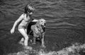 Child playing with dog in sea water on beach. Royalty Free Stock Photo