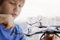 Child playing with drone. Boy near the window holding quadrocopter in his hand. Technology, leisure toys concept