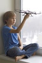 Child playing with drone. Boy sitting on window sill and holding quadrocopter in his hand. Technology, leisure toys Royalty Free Stock Photo