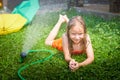 Child playing with garden sprinkler. Summer outdoor water fun in backyard. Ggirl play with hose watering grass. Kid Royalty Free Stock Photo