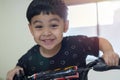 Child playing at home. Head portait of a little boy with smile in black T-shirt rides a tricycle at home in the room Royalty Free Stock Photo