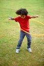 Child, playing and hula hoop on field on holiday, green grass and sunshine with energy in city. Young boy, mexican and