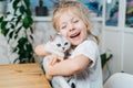 child playing with little cat. A little girl holds a white kitten. A little girl snuggles up to a cute pet and smiles while Royalty Free Stock Photo