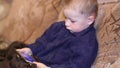 Child Playing with Mobile Phone on the Sofa. Chirld hands texting on smartphone in room. He holds a modern mobile phone