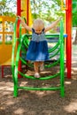Child playing on outdoor playground. Little baby girl plays on school or kindergarten yard. Active kid on colorful swing Royalty Free Stock Photo
